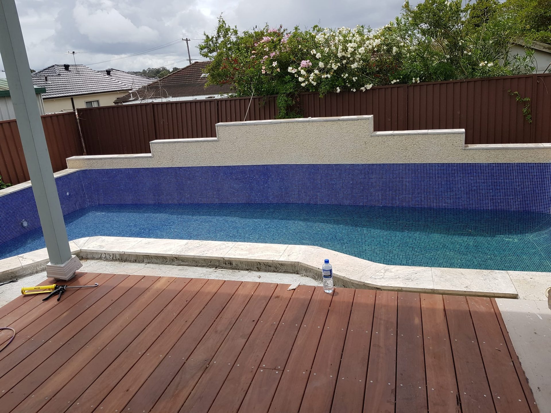 Completed swimming pool with water filled and timber deck — pool tiling Sydney