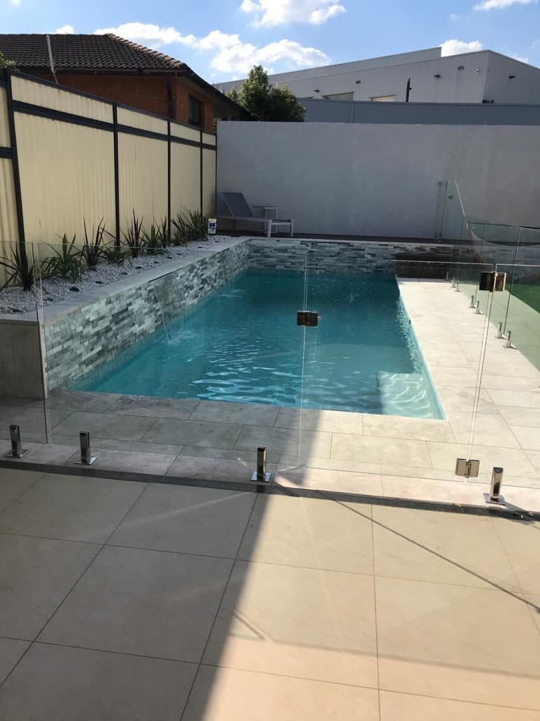 Pool with natural stone feature wall and water feature — pool tiling Sydney